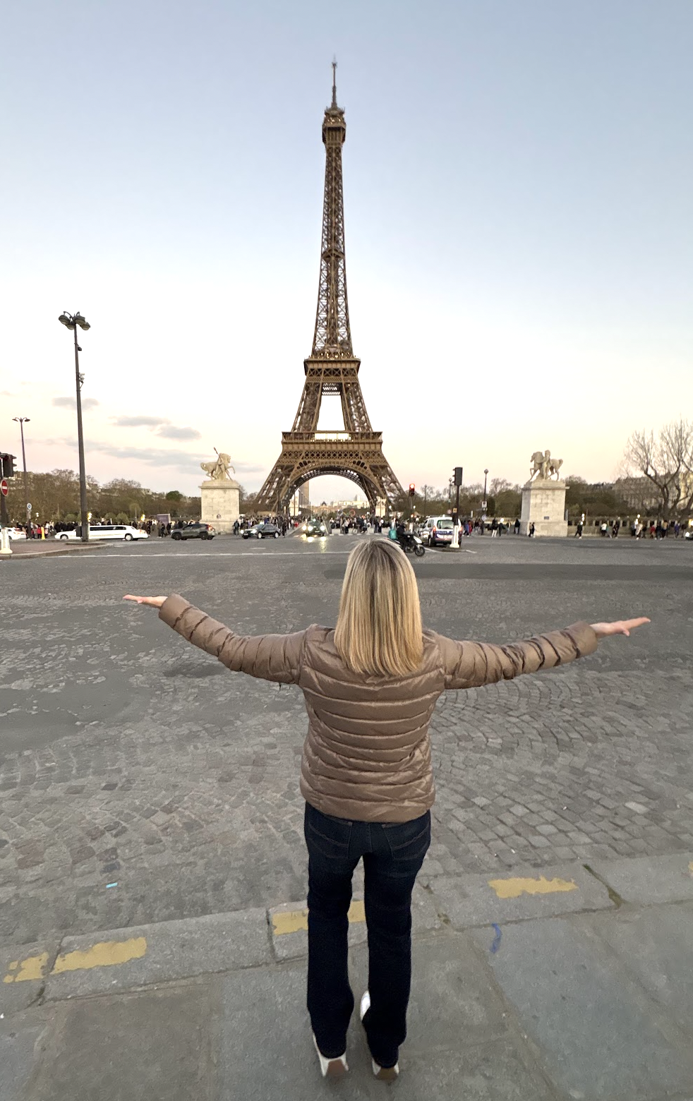 Melissa standing with arms outstretched in front of the Eiffel Tower in Paris