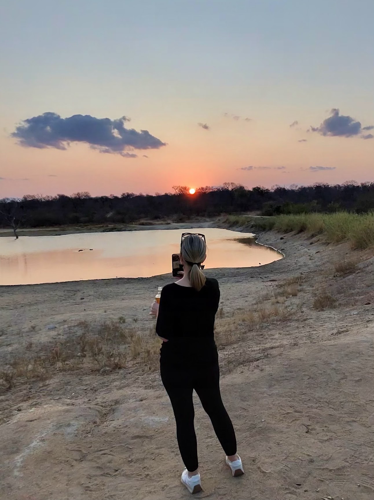 Traveler capturing an African safari sunset over a watering hole