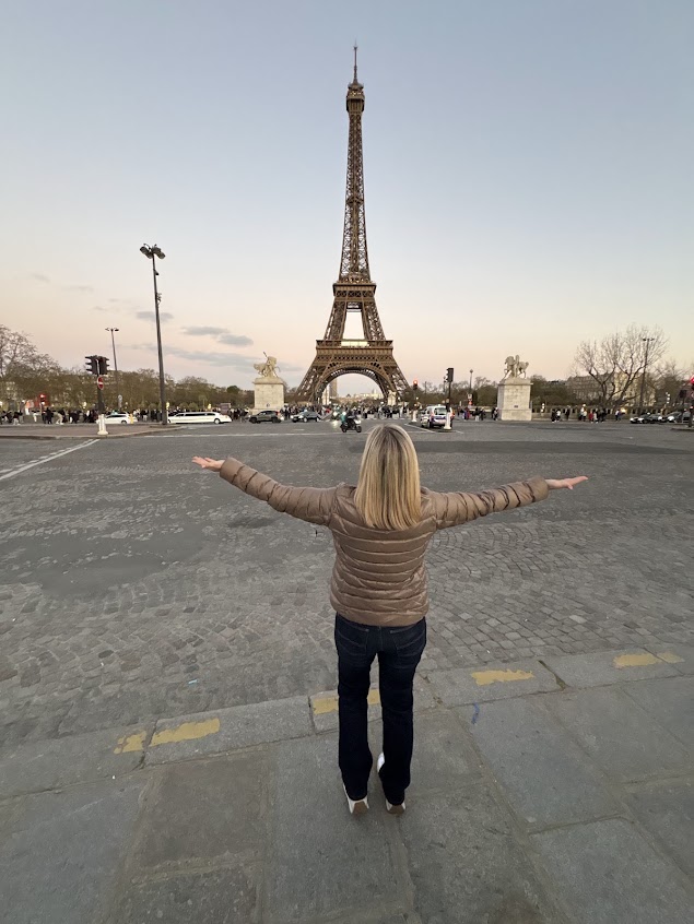 Melissa facing the Eiffel Tower in Paris with her arms outstretched