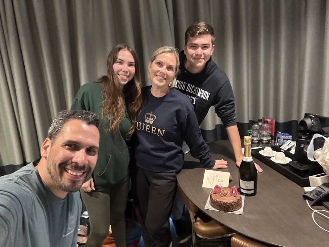 Melissa celebrating her 50th birthday in London with her family, cake, and Prosecco