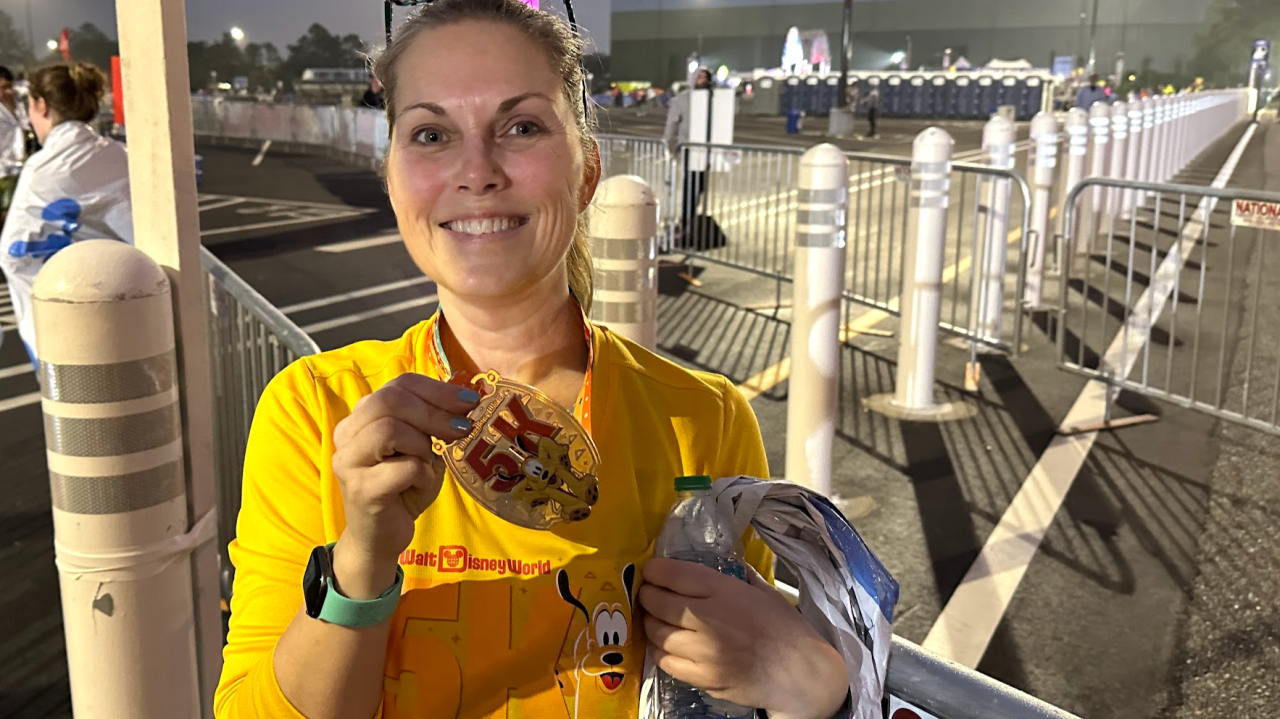 Melissa holding her runDisney 5K finisher medal at Walt Disney World