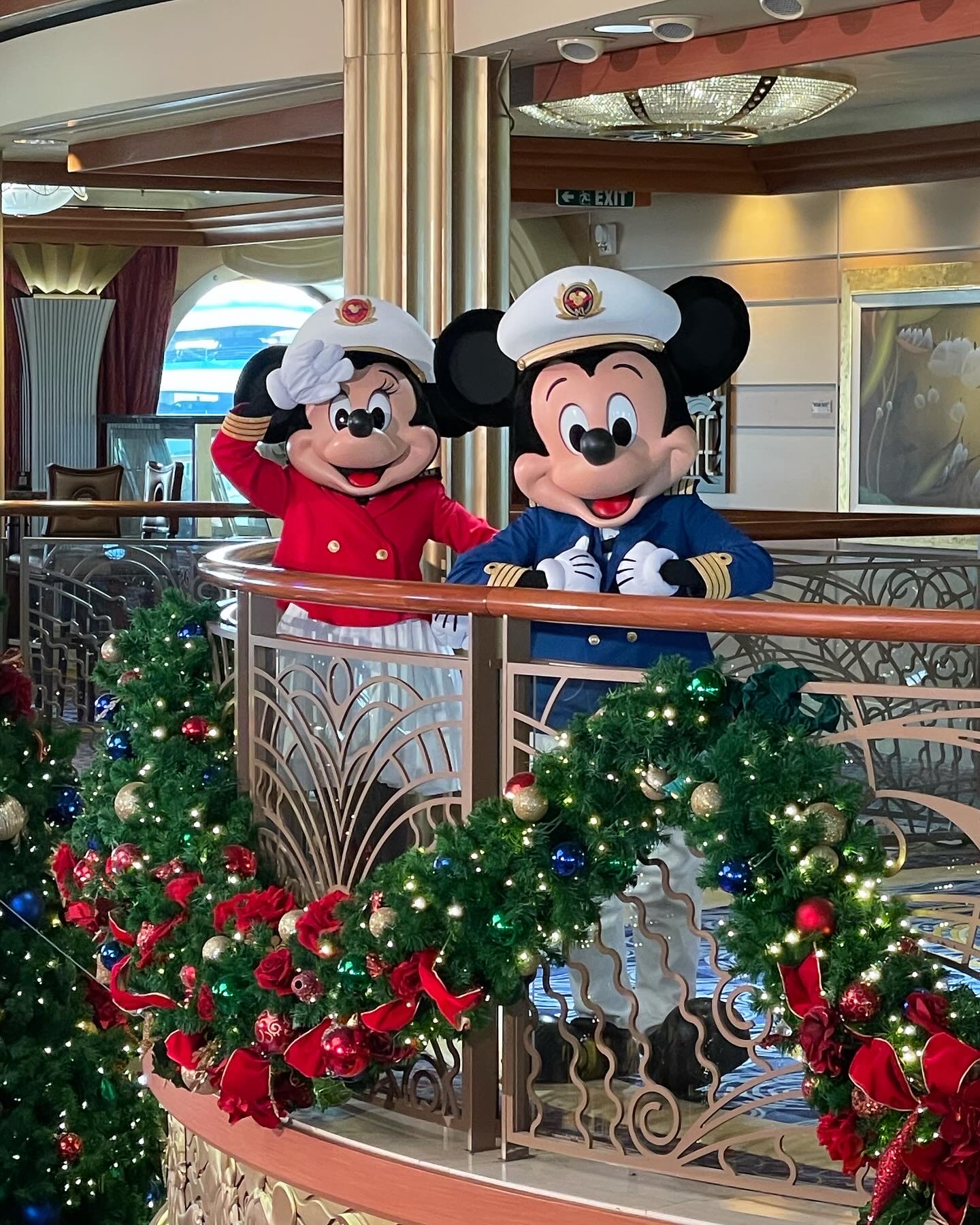Minnie and Mickey Mouse in captain outfits aboard a holiday-decorated Disney cruise ship