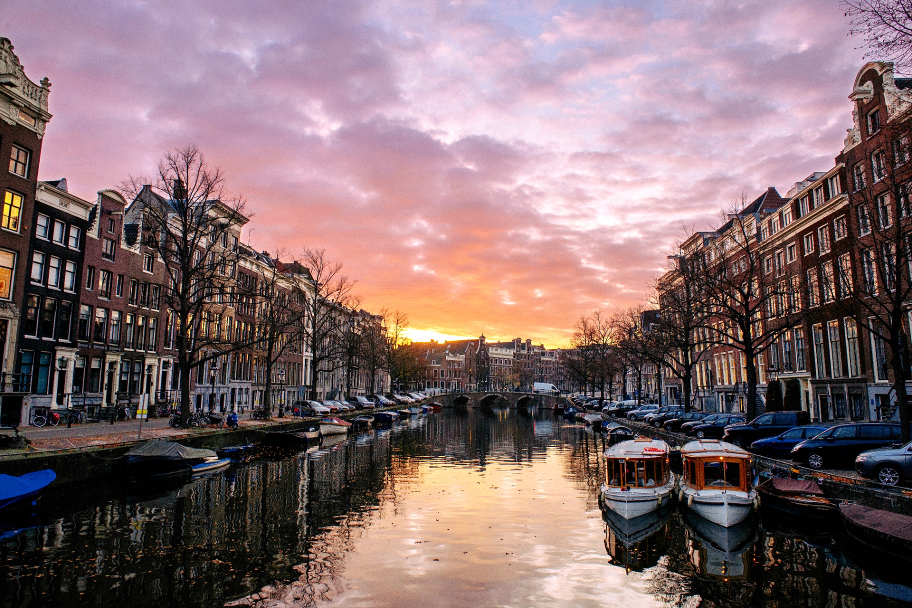 Sunset over an Amsterdam canal with historic houses and boats